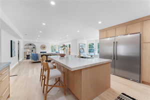 Kitchen featuring light brown cabinets, built in refrigerator, recessed lighting, plenty of natural light, and light wood-style floors