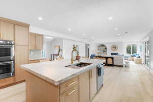Kitchen featuring light brown cabinetry, light wood finished floors, appliances with stainless steel finishes, recessed lighting, and open floor plan