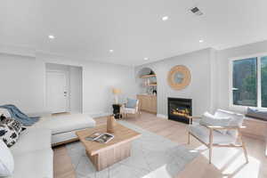 Living area featuring recessed lighting, a glass covered fireplace, and light wood-type flooring