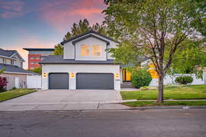 View of front of home featuring a garage, a front lawn, concrete driveway, stucco siding, and roof with shingles