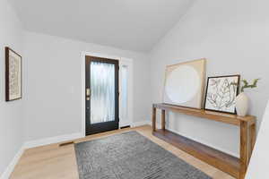 Foyer entrance with light wood-style flooring and lofted ceiling