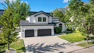 View of front of house featuring stucco siding, a front lawn, a garage, a shingled roof, and driveway