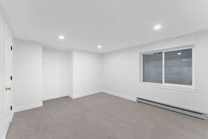 Empty room with baseboard heating, light colored carpet, and recessed lighting