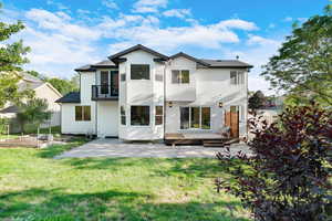 Back of property featuring a balcony, a patio area, stucco siding, and a garden