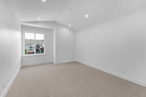 Empty room featuring lofted ceiling, light carpet, and recessed lighting