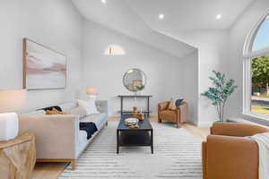 Living room with light wood-type flooring, recessed lighting, and high vaulted ceiling