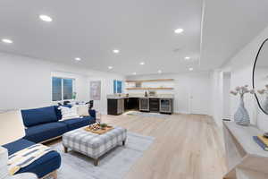 Living room with bar, light wood-type flooring, beverage cooler, and recessed lighting