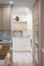Kitchen with open shelves, double wall oven, light wood-style floors, backsplash, and brown cabinets