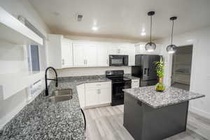 Kitchen featuring dark stone countertops, black appliances, white cabinets, and recessed lighting