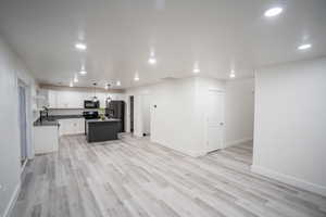 Kitchen with decorative light fixtures, a kitchen island, white cabinetry, light wood-style flooring, and recessed lighting