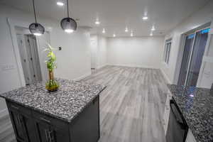 Kitchen with light wood finished floors, dark stone countertops, recessed lighting, and black dishwasher