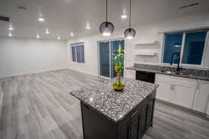 Kitchen with white cabinets, light stone counters, pendant lighting, open shelves, and dark cabinets