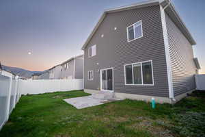 Back of house at dusk featuring a fenced backyard and entry steps