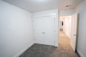 Unfurnished bedroom with dark colored carpet and a closet