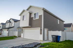 View of property exterior with a garage, concrete driveway, and a residential view