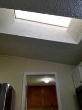 Detailed view of a textured ceiling, black fridge, and crown molding