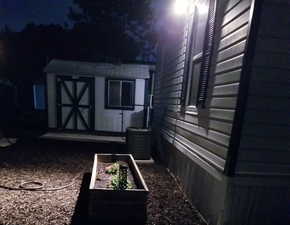 Property exterior at night featuring a storage shed and a central AC unit