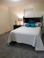 Bedroom featuring a textured ceiling and dark carpet