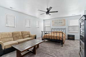 Carpeted bedroom featuring a textured ceiling and a ceiling fan
