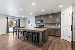 Kitchen featuring a kitchen island with sink, light stone countertops, a textured ceiling, recessed lighting, and backsplash