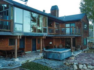 Rear view of house with a patio, a hot tub, and a chimney
