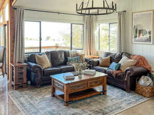 Living area featuring lofted ceiling, wood walls, light tile patterned flooring, a chandelier, and wood ceiling