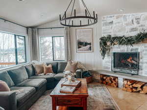 Tiled living room featuring a stone fireplace, vaulted ceiling, recessed lighting, and wooden walls