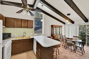 Kitchen featuring a peninsula, white appliances, light countertops, and healthy amount of natural light