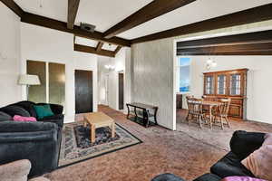Carpeted living room with beam ceiling and a chandelier
