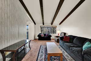 Carpeted living area featuring beam ceiling