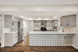 Kitchen with tasteful backsplash, a raised ceiling, a peninsula, appliances with stainless steel finishes, and recessed lighting