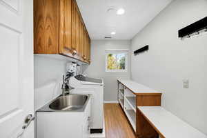 Laundry area featuring light wood-type flooring, washer and dryer, and recessed lighting
