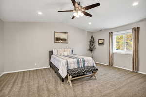 Carpeted bedroom with ceiling fan, vaulted ceiling, and recessed lighting