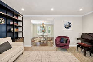 Living area with crown molding, recessed lighting, wood finished floors, and a chandelier