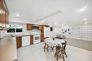 Kitchen with white appliances, open floor plan, brown cabinetry, recessed lighting, and light floors