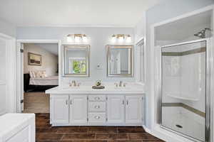 Ensuite bathroom featuring double vanity, wood finish floors, a shower stall, and a closet