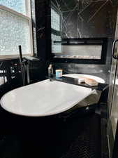 Primary full bathroom featuring a freestanding tub, tile walls, and a marble finish shower