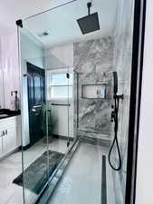 Full bathroom with a marble finish shower and vanity