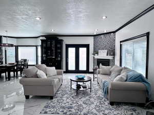 Living area featuring light marble finish flooring, a textured ceiling, crown molding, healthy amount of natural light, and recessed lighting