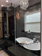 Primary full bathroom featuring a freestanding tub, tile walls, and a marble finish shower
