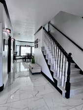 Stairway featuring baseboards, a textured ceiling, and marble finish floors