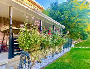 View of home's exterior featuring front yard, and roses in front of covered porch