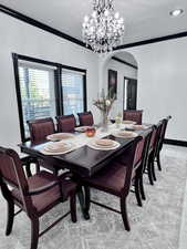 Formal dining area featuring ornamental molding, arched walkways, and a chandelier
