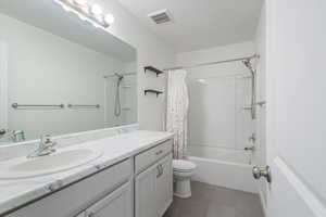 Full bath featuring vanity, shower / bath combination with curtain, and dark tile patterned floors