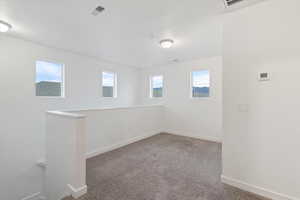 Carpeted spare room featuring baseboards