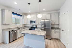 Kitchen featuring stainless steel appliances, light wood-style flooring, white cabinets, a center island, and recessed lighting