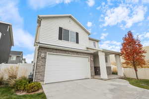 Traditional-style house with stone siding, a garage, and concrete driveway