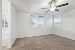 Unfurnished room featuring light carpet and a ceiling fan