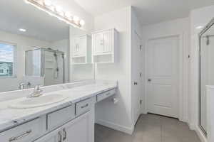 Full bathroom with a stall shower, vanity, and light tile patterned flooring