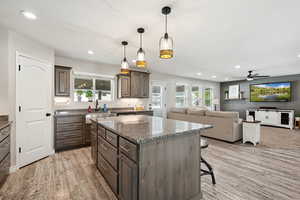 Kitchen with hanging light fixtures, a kitchen breakfast bar, recessed lighting, dark stone counters, and open floor plan